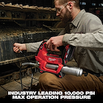 A person operates a red Milwaukee power tool designed for industrial use on heavy machinery, featuring a max operation pressure of 10,000 PSI.