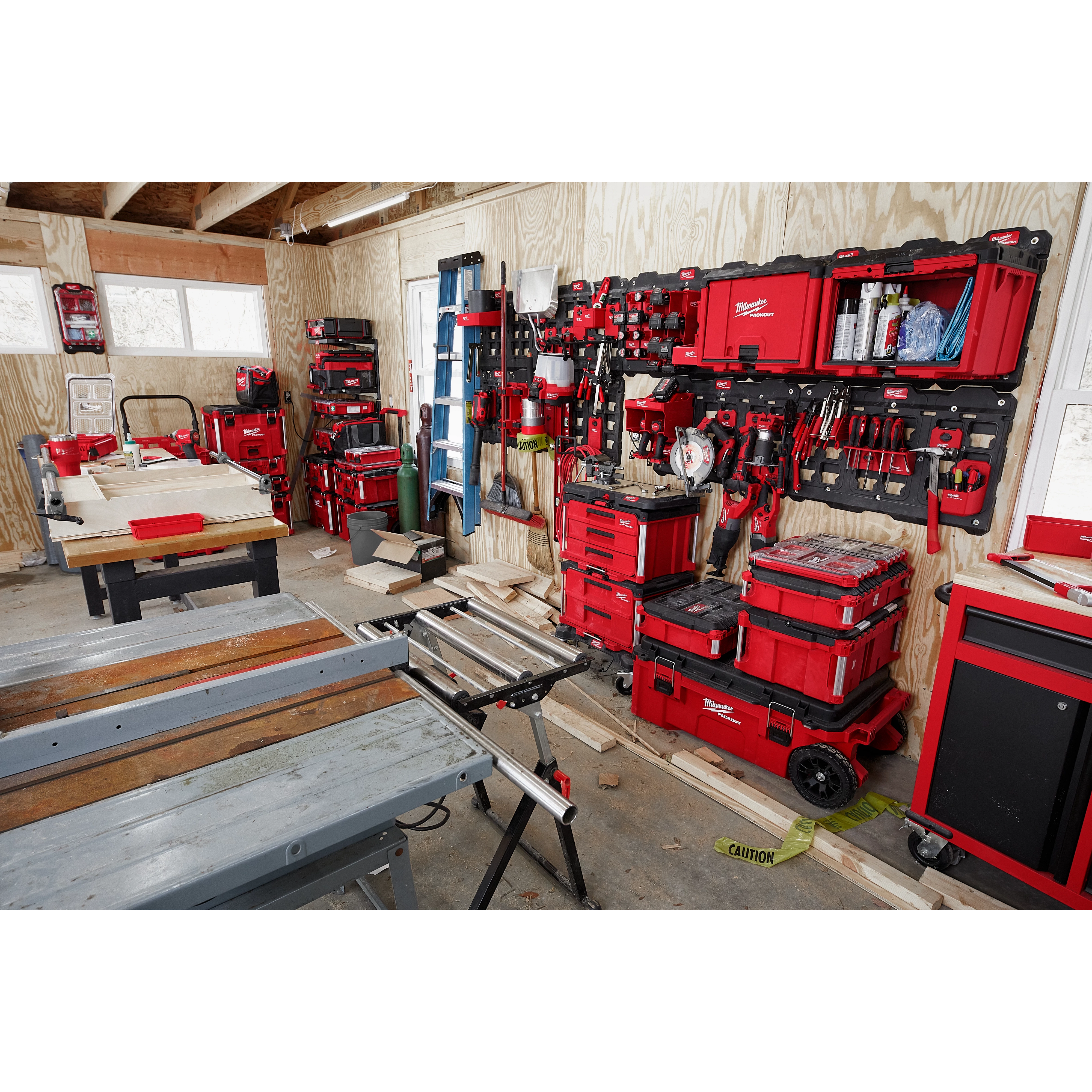 A workshop with tools and equipment organized on red PACKOUT Large Wall Plates, including stacked toolboxes, saws, and hand tools.