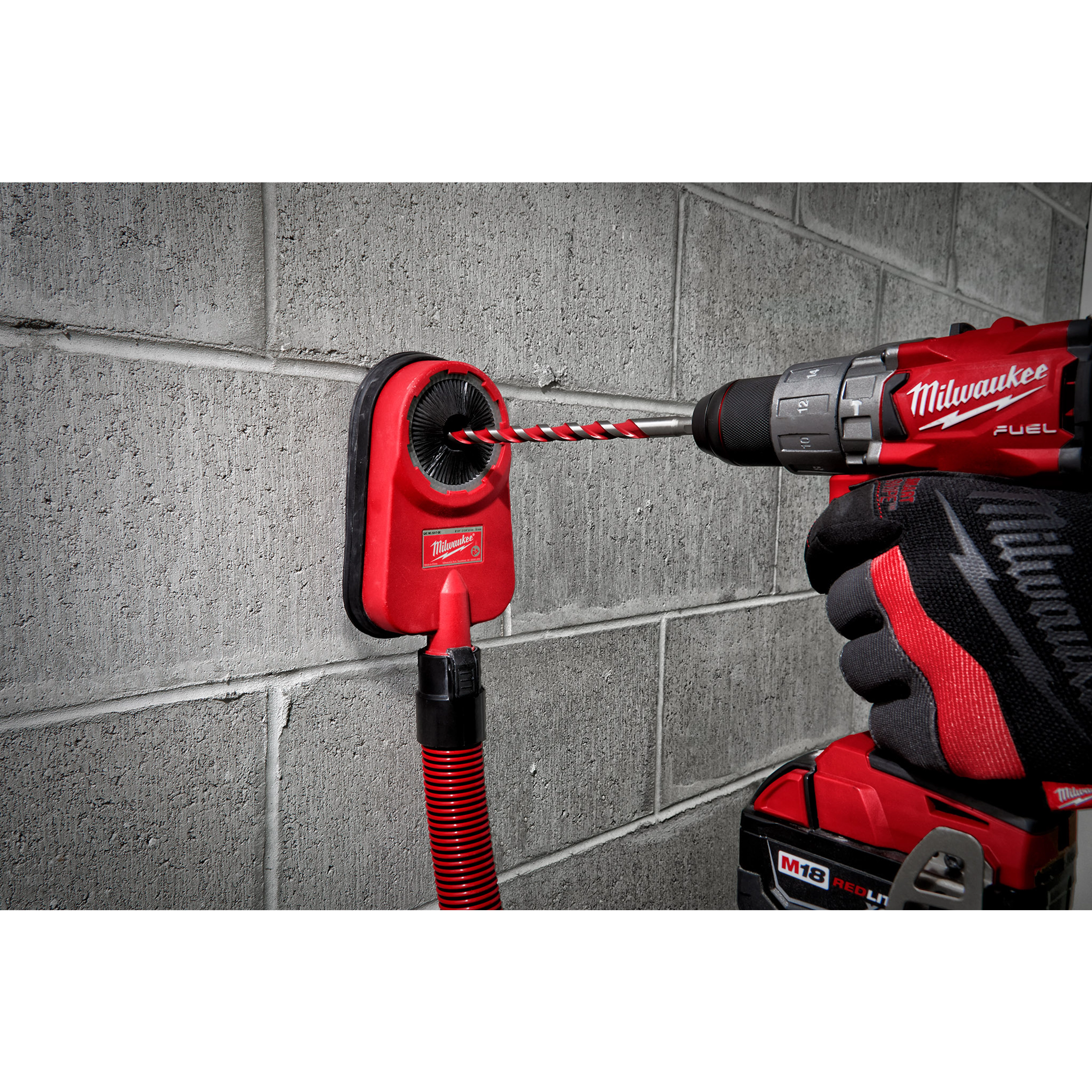 Hammer drill with a 1/2" X 10" X 12" hammer drill bit drilling into a concrete wall, with a dust extractor attached.