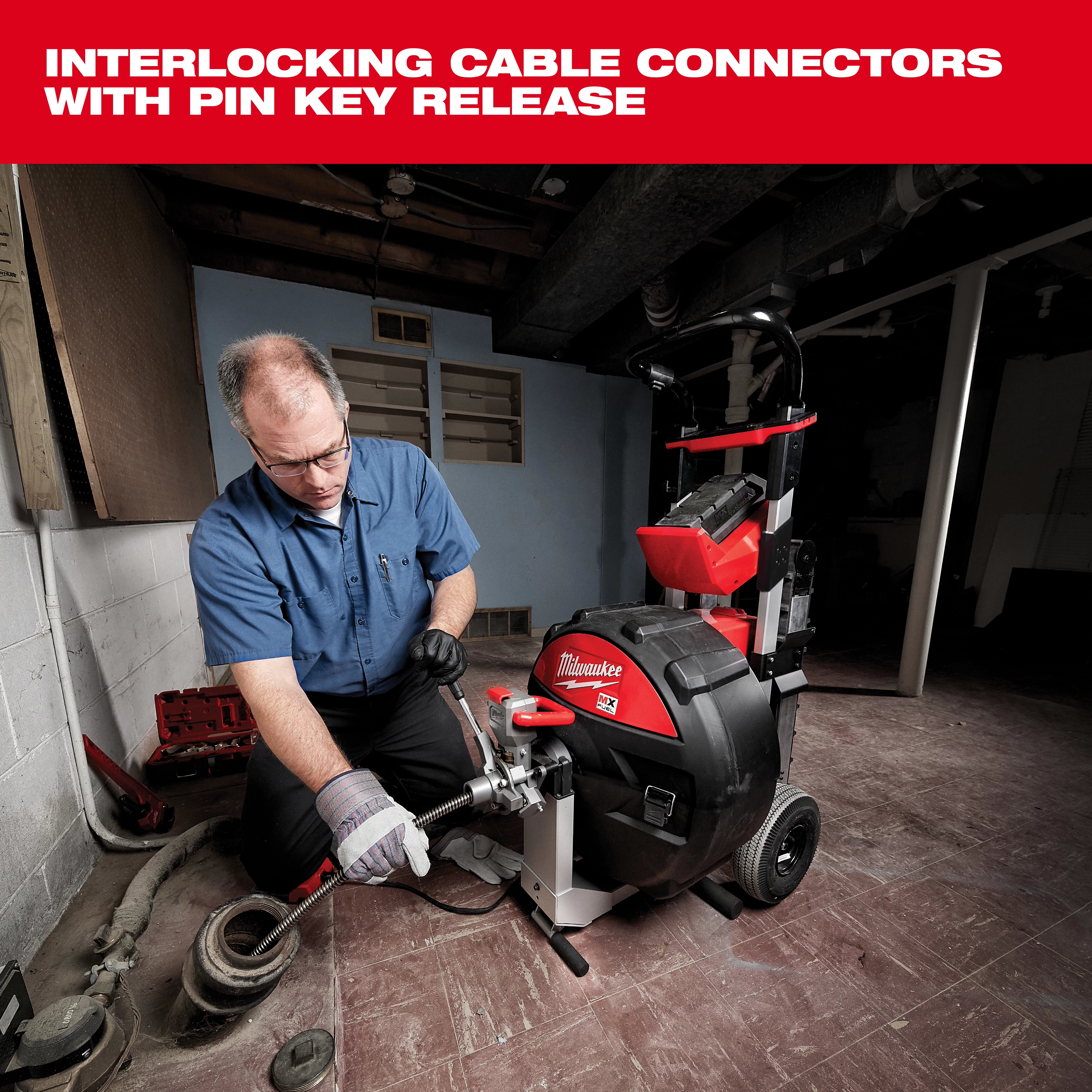 A man wearing gloves operates a Milwaukee cable connector machine in a basement. The machine features interlocking cable connectors with a pin key release, designed for heavy-duty cable work and ease of use. It has red and black components, and is equipped with wheels for mobility.
