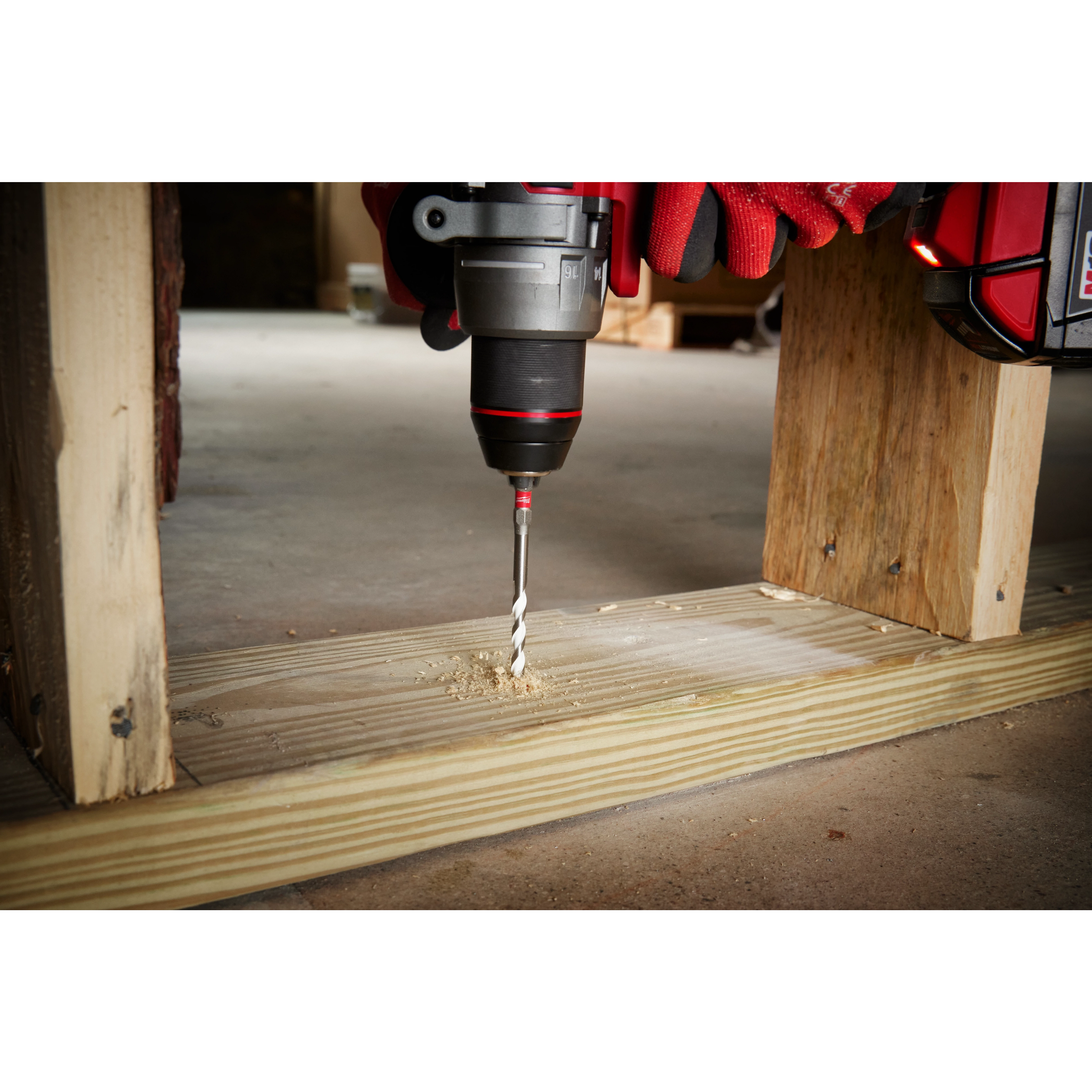 Handheld drill with 1/4" x 4" x 6" SHOCKWAVE Impact Duty Carbide Multi-Material Drill Bit drilling through a wooden plank.
