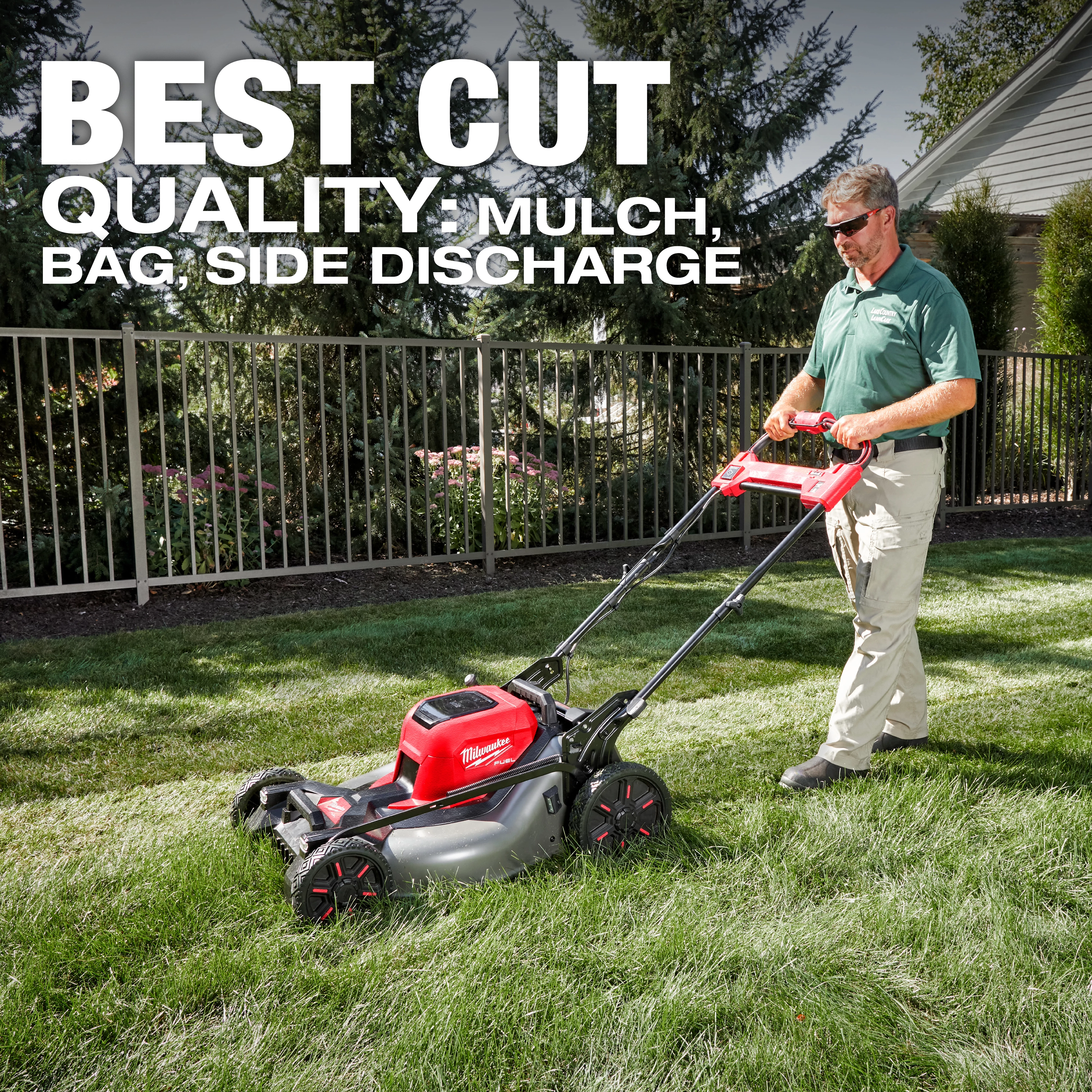 A person operates an M18 FUEL™ 21" Self-Propelled Dual Battery Mower on a lawn. The mower is red and black with a silver base. Text reads "BEST CUT QUALITY: MULCH, BAG, SIDE DISCHARGE." Trees and a fence are in the background.
