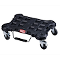 The PACKOUT Dolly is a black, heavy-duty rolling platform with a handle and four caster wheels, designed for transporting tools.