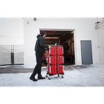 A person pushes a 366pc. Master Mechanics Hand Tool Set with PACKOUT™ Drawers and Dolly into a garage. The tool set is stacked in red, wheeled drawers, and the scene is outdoors with snow on the ground.