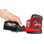 A person holds a Milwaukee M18™ Random Orbit Sander by its dust collection bag. The sander is red and black with a black branded bag. The image displays the sander's side profile with visible control buttons and branding.
