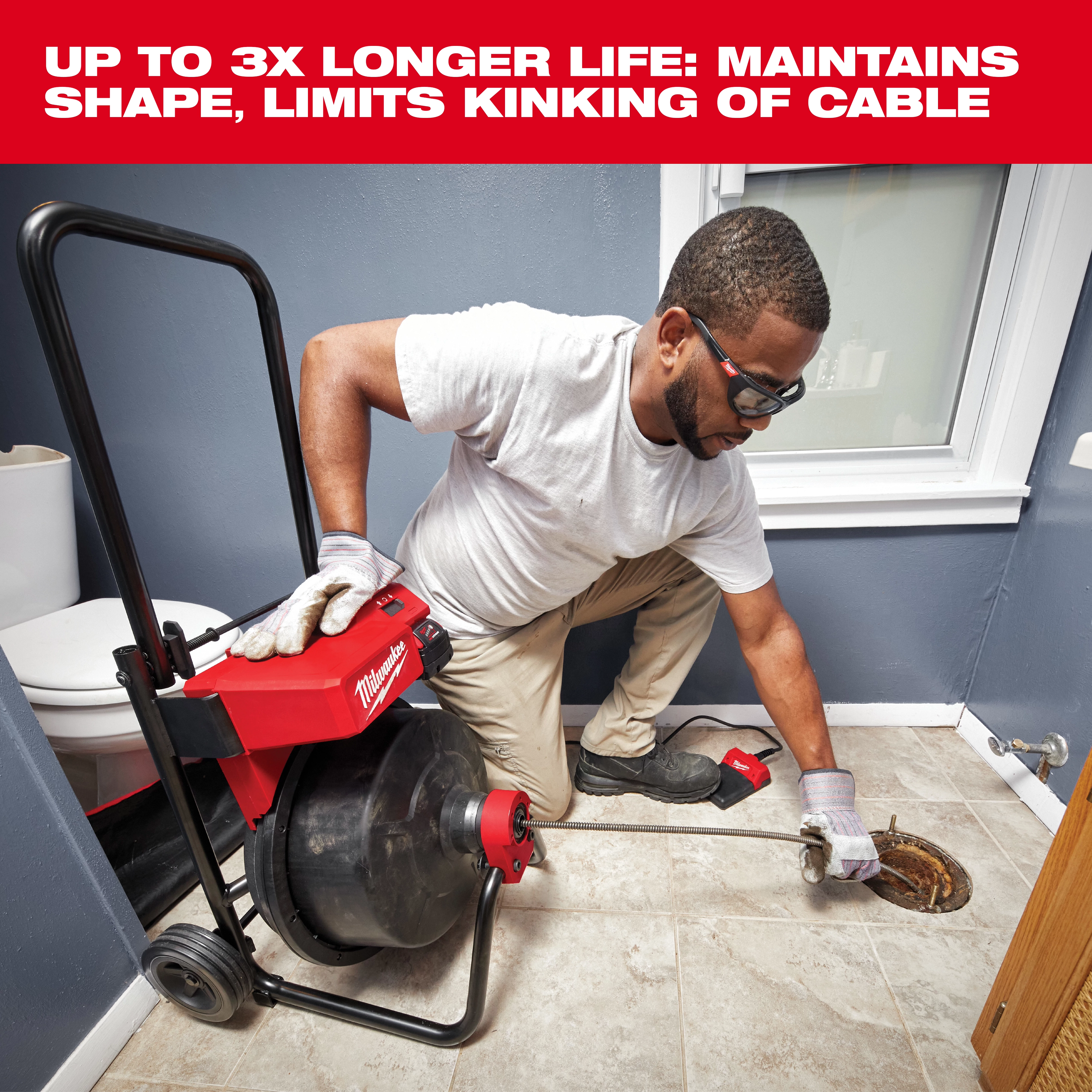 A person operates the Milwaukee drain snake tool in a bathroom, feeding the cable into a floor drain. The drain snake is mounted on a wheeled cart with cable storage and has a handle for ease of use. The text above reads, "Up to 3x longer life: maintains shape, limits kinking of cable."