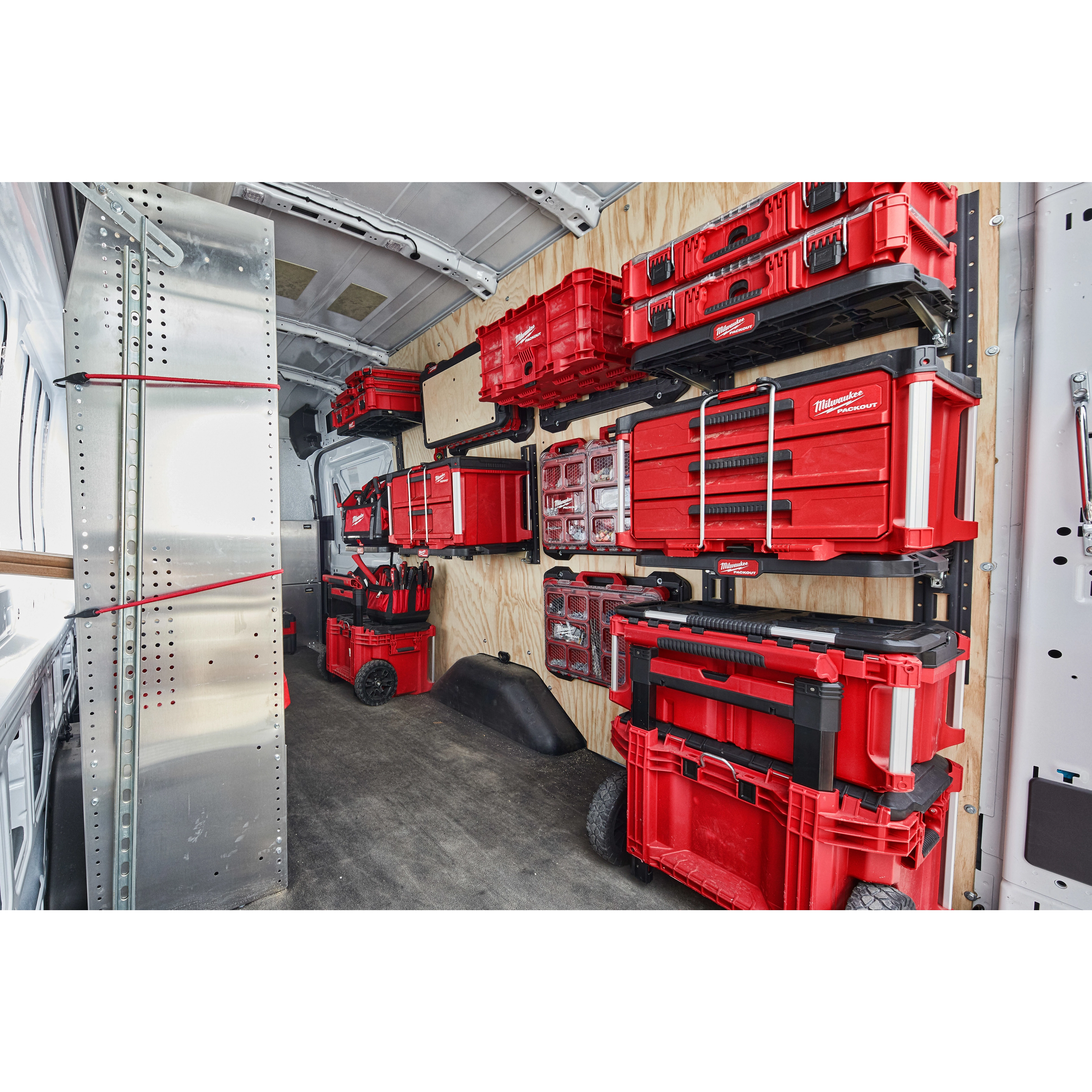 Organized PACKOUT Racking Kit in a van, displaying various red storage boxes and tool organizers securely mounted and neatly arranged.