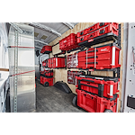 Organized PACKOUT Racking Kit in a van, displaying various red storage boxes and tool organizers securely mounted and neatly arranged.
