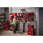 Man organizing tools in a garage using March 2023 Packout Shop Storage system with red toolboxes and wall-mounted storage units.
