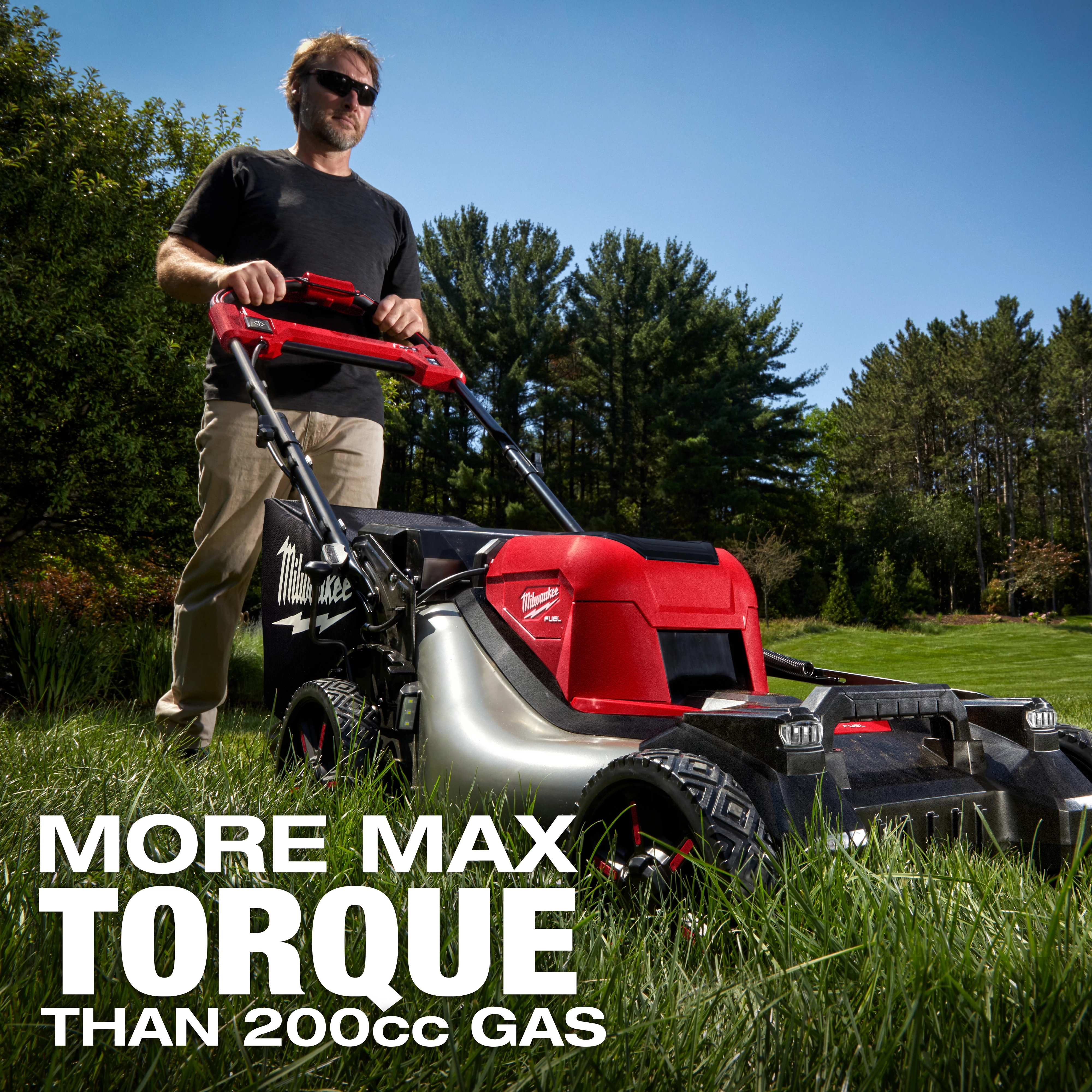 A person uses the M18 FUEL™ 21" Self-Propelled Dual Battery Mower on a grassy lawn with trees in the background. The text on the image reads "MORE MAX TORQUE THAN 200cc GAS".