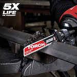 Nitrus Carbide Life Claim TORCH saw blade cutting through thick metal. The blade sits in a machine, held by a gloved hand. Text in the top left corner indicates "5X LIFE." The product is designed for cast iron and thick metal.